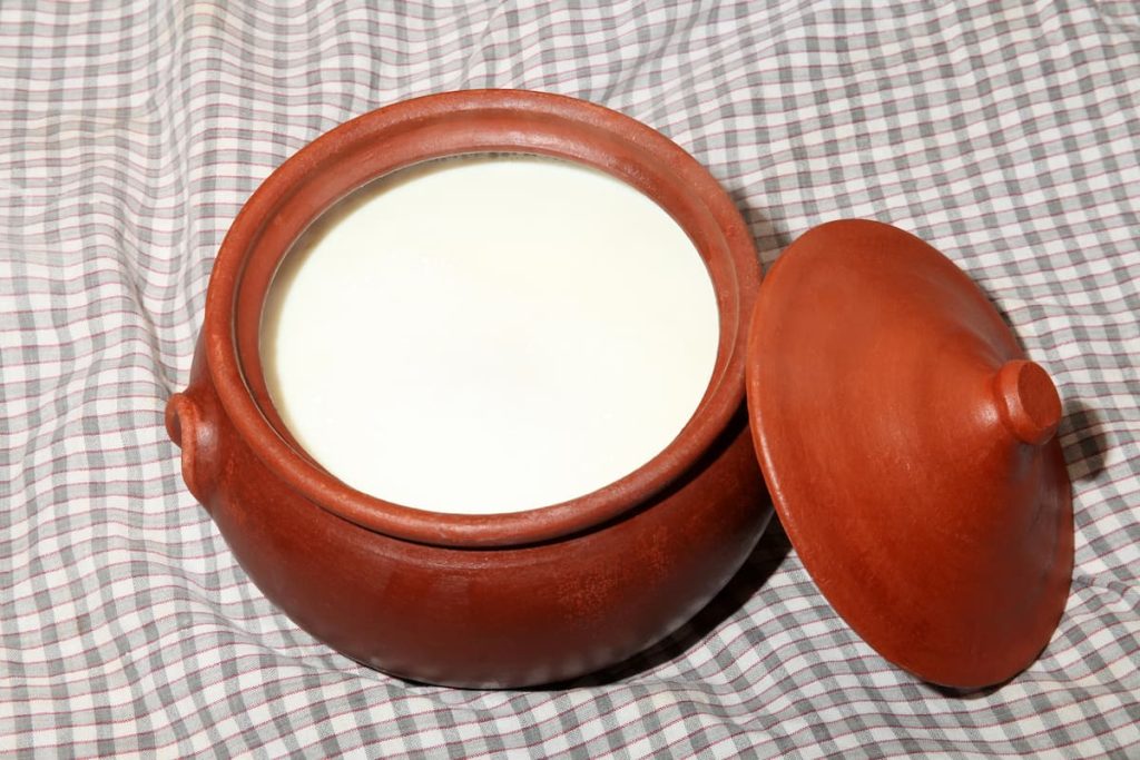 Imagem mostra panela de barro usada para preparar a receita de iogurte natural caseiro consistente.