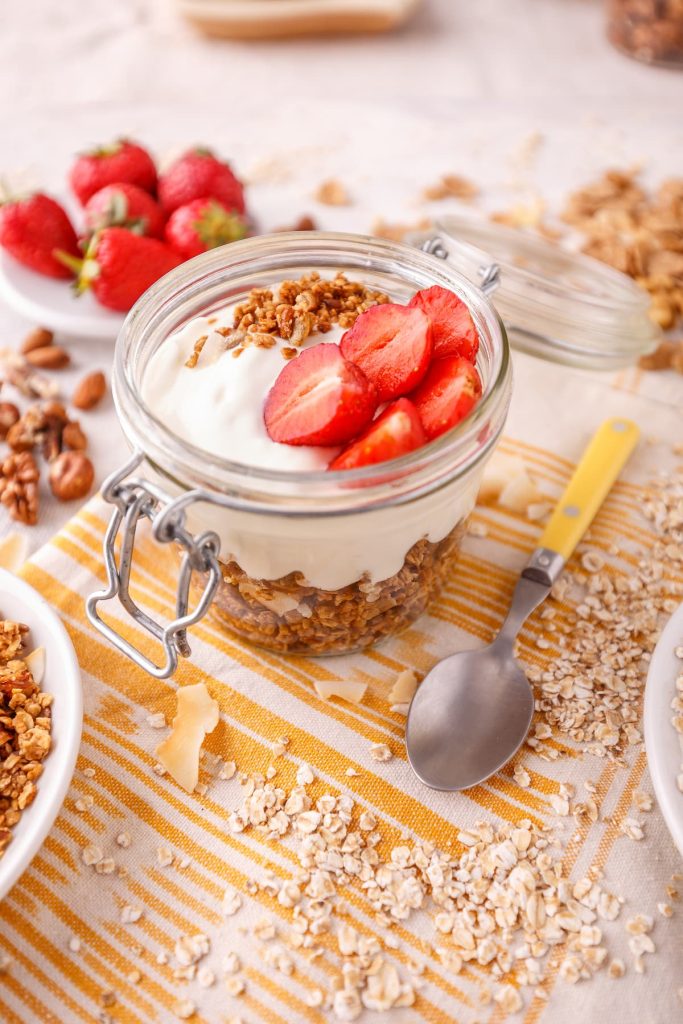 Imagem mostra iogurte natural caseiro com morango e granola.