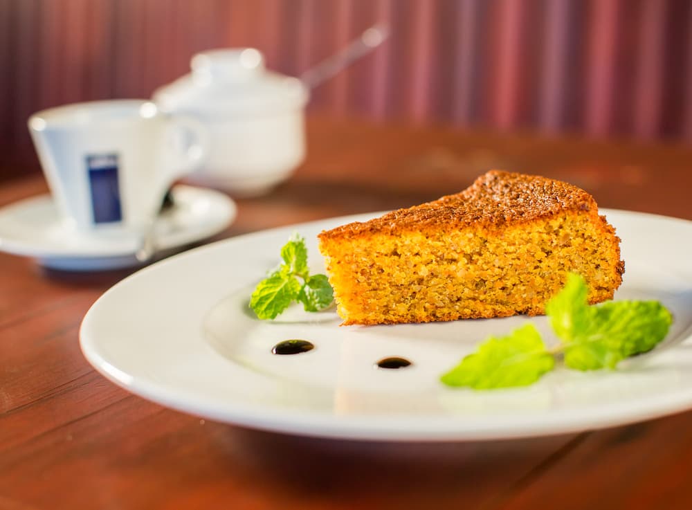 Imagem mostra bolo de cenoura acompanhado de um bela e saborosa xícara de café.