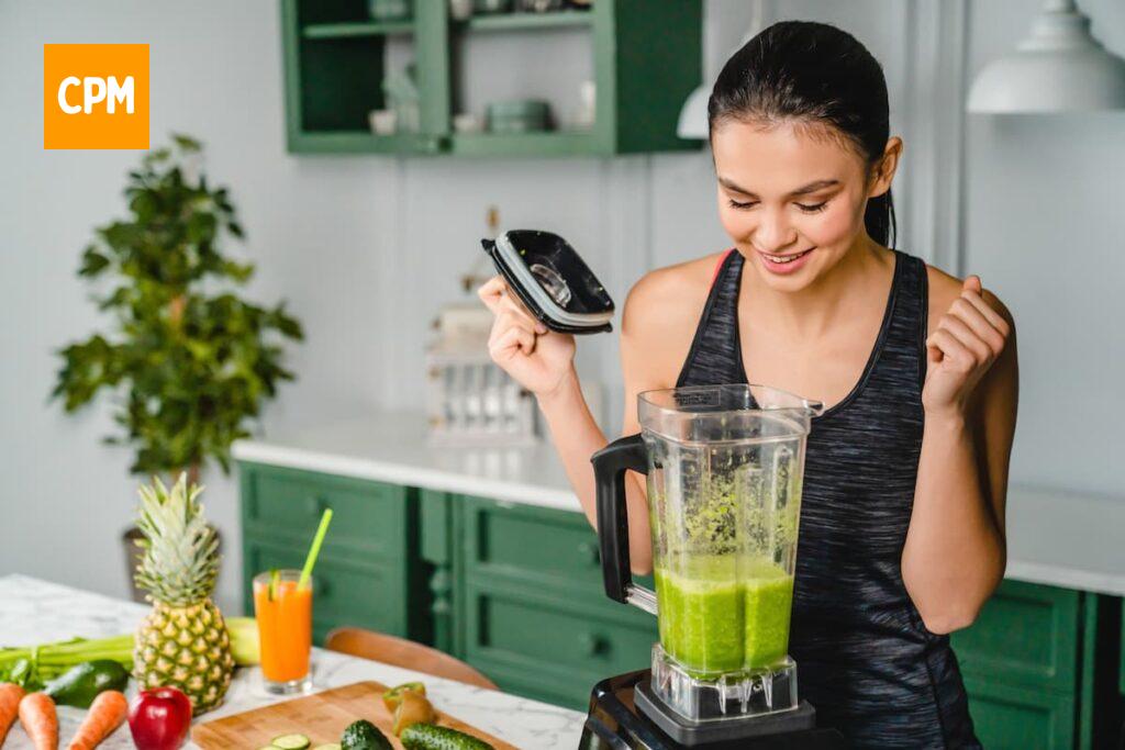 Imagem mostra jovem preparando suco saudável.