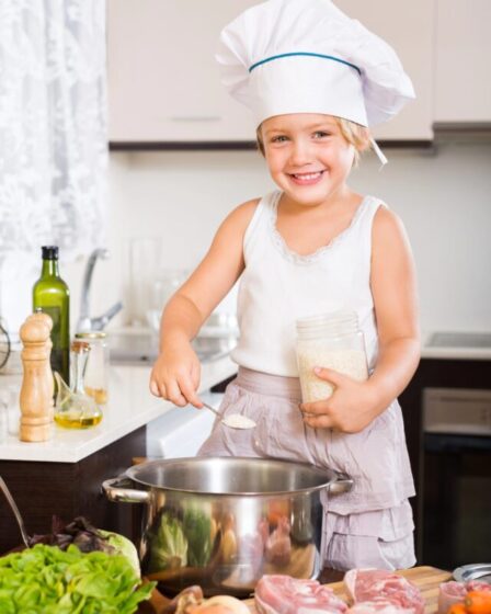 Imagem mostra Criança com roupa de chef na cozinha fazendo cookie