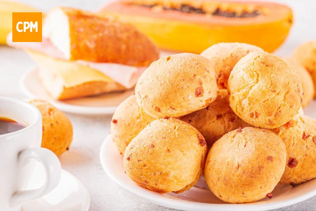 Imagem mostra uma mesa de café da manhã perfeita, acompanhada de um delicioso pão de queijo.