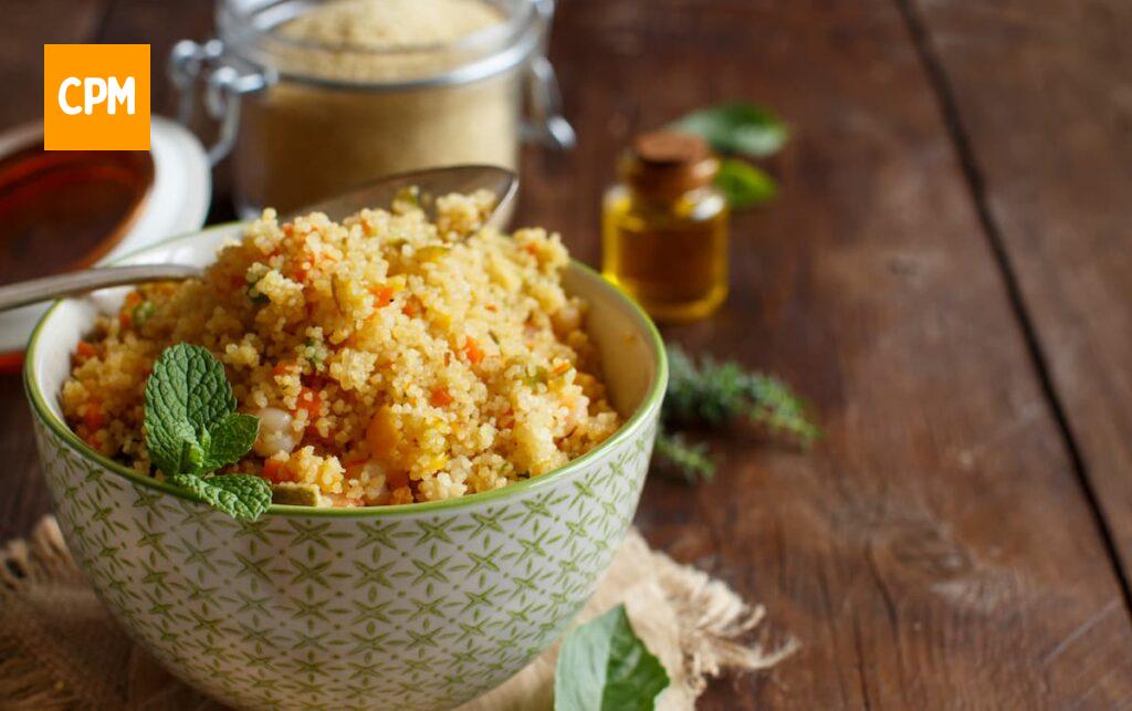 Imagem mostra uma tigela de cuscuz paulista com camarão e legumes.