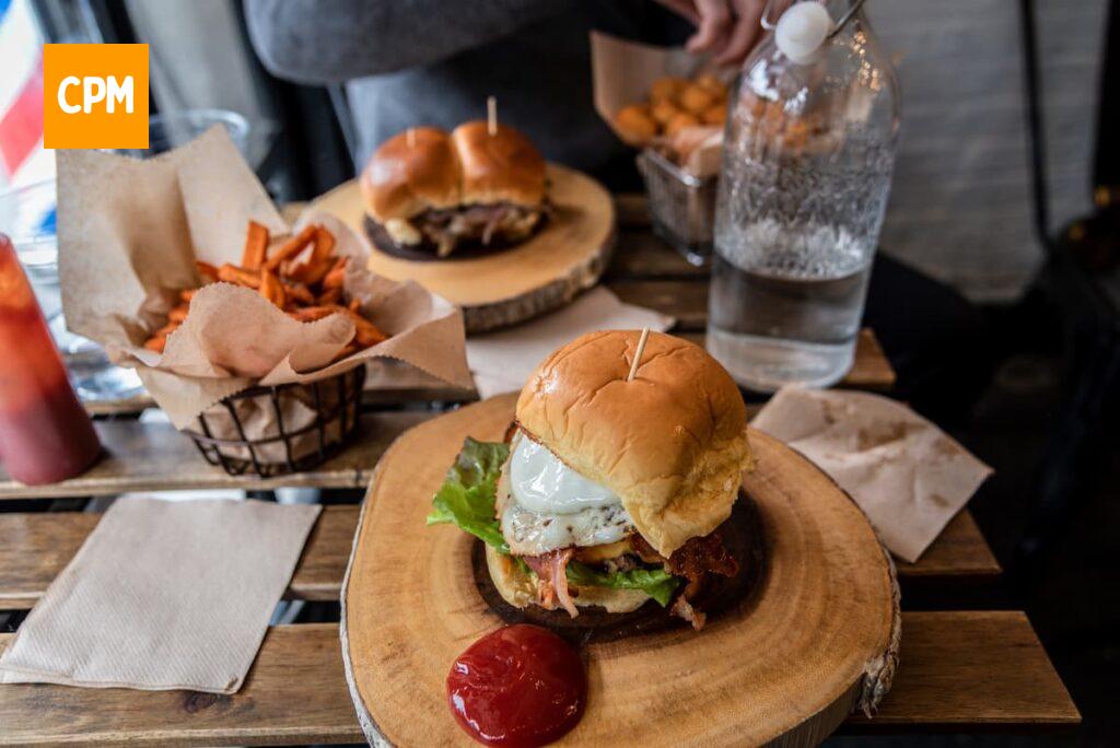 Imagem mostra um delicioso hambúrguer gourmet servido acompanhado de batata frita.