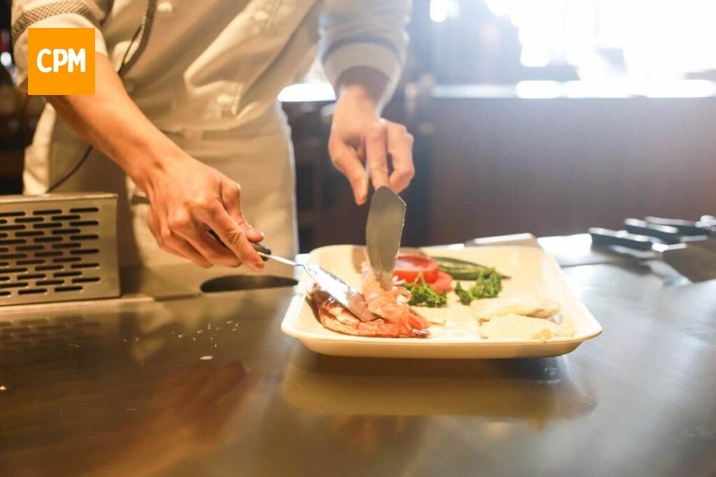 Imagem mostra chefe de cozinha montando prato em restaurante.