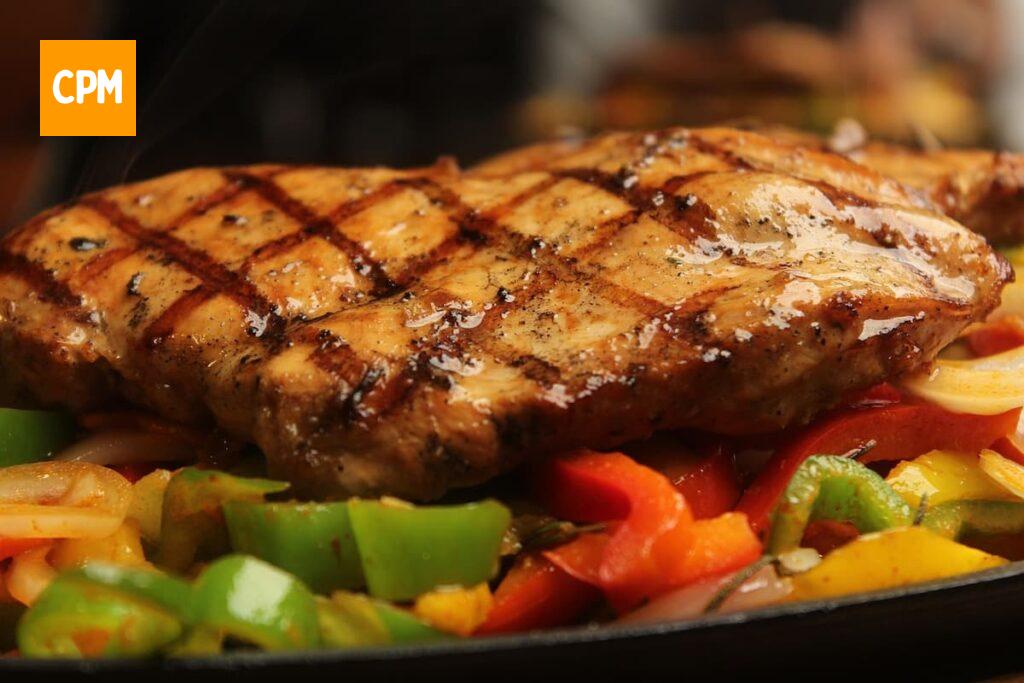 Imagem mostra corte de carne grelhado e suculento servido com salada de legumes.