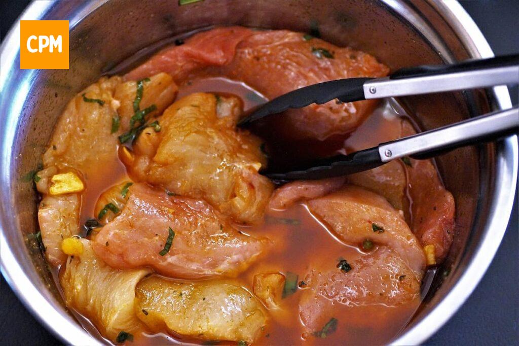 Imagem mostra frango marinado com ervas frescas, uma das melhores marinadas para frango.