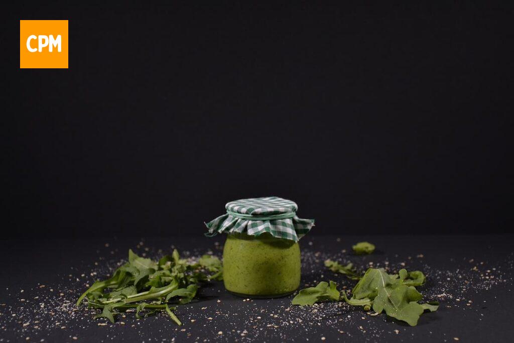 Imagem mostra molho pesto armazenado em u pote, uma das formas de conservar sua receita de molho pesto por mais tempo.